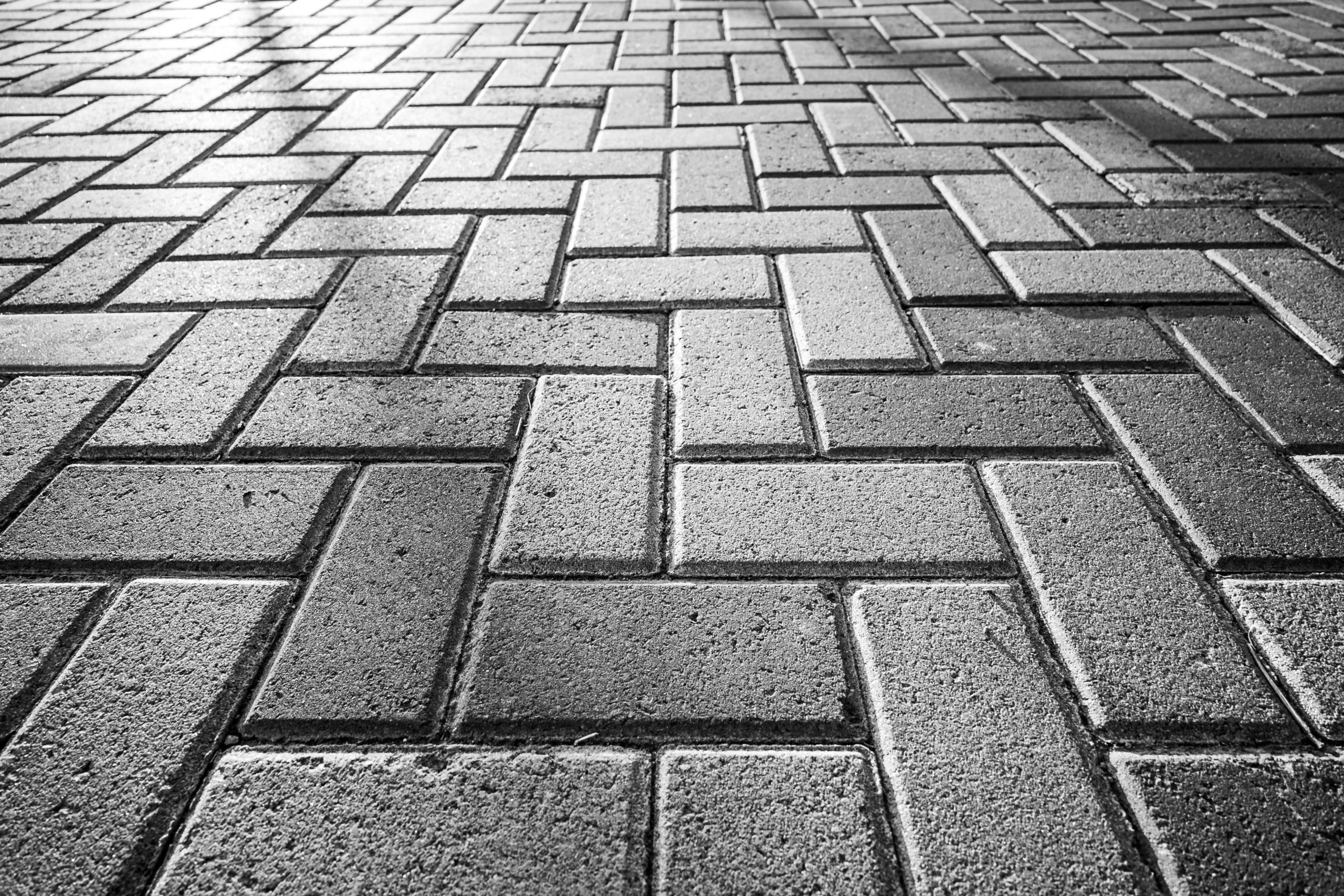A detailed black and white image of herringbone brick pavement showcasing texture and pattern.